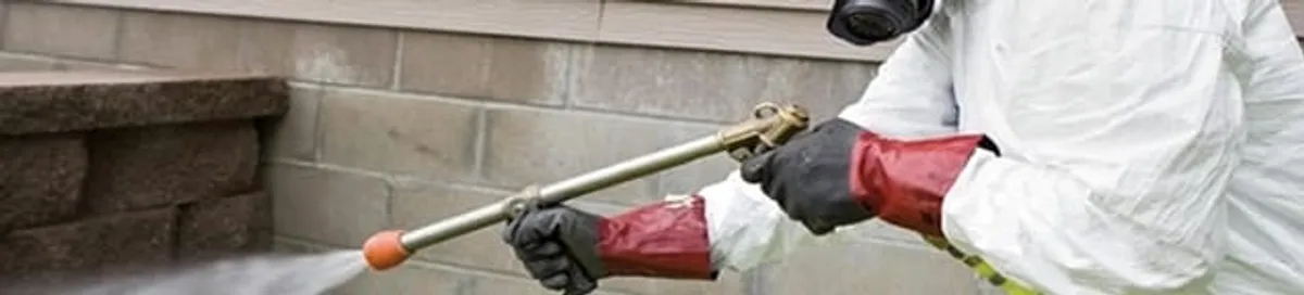 Pest control technician applying exterior insect treatment along a home foundation in West Palm Beach, FL