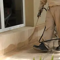 General pest control technician spraying exterior perimeter around a home in West Palm Beach, FL