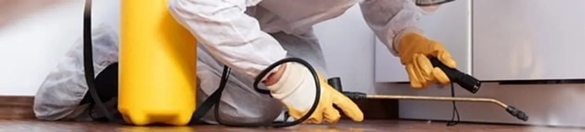 Roach exterminator treating cracks and crevices along kitchen baseboards in West Palm Beach, FL