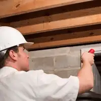 Termite inspection technician checking a basement wall and framing for termite activity in West Palm Beach, FL